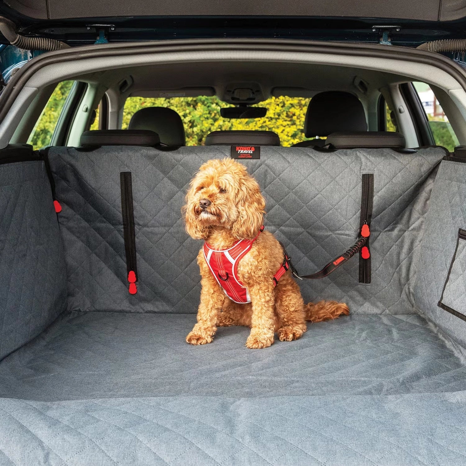KONG Protector de Maletero Ultimate con Correa de Seguridad instalado en un SUV, con perro usando arnés sobre la superficie acolchada.