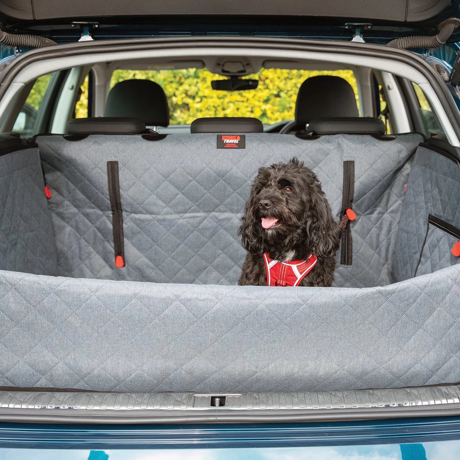 KONG Protector de Maletero Ultimate con Correa de Seguridad instalado en un SUV, con perro usando arnés sobre la superficie acolchada.