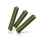 Naturalistic Dental Stick Menta para perros, caja verde y negra con sticks dentales verdes y perro blanco sosteniendo uno.